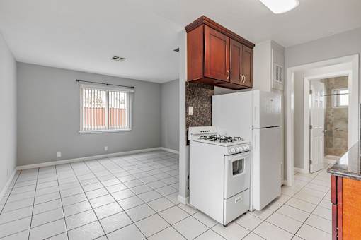 A kitchen with white appliances and a white tile floor.