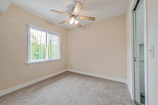 A room with a ceiling fan and a window with blinds.