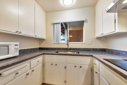 A kitchen with white cabinets and a black countertop.