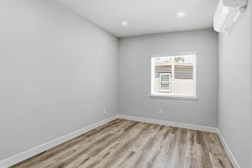A room with a window and wooden flooring.