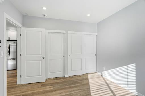 Three white doors are in a room with wooden floors.