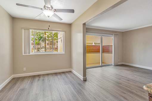 A room with a ceiling fan and sliding glass doors.