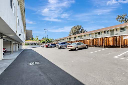 A parking lot with cars parked and a building on the left.