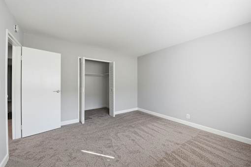 A room with a carpeted floor and two open doors.