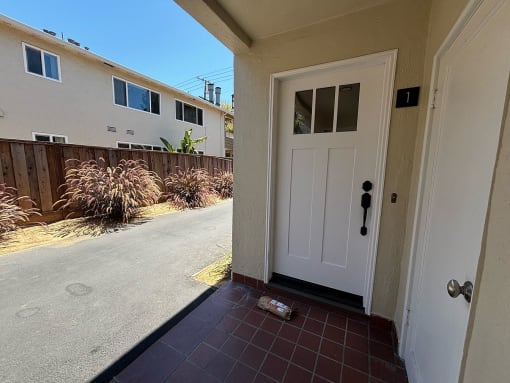 the entrance to a home with a white door and a driveway