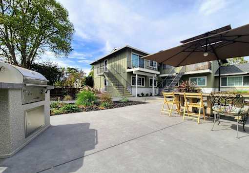 A patio with a table and chairs is in front of a house.