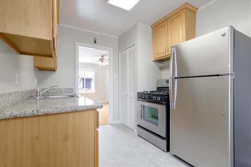 A kitchen with a refrigerator, oven, and sink.