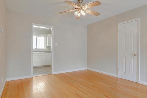 A room with a ceiling fan and wooden floors.