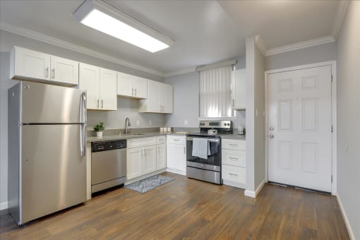 A kitchen with stainless steel appliances and white cabinets.