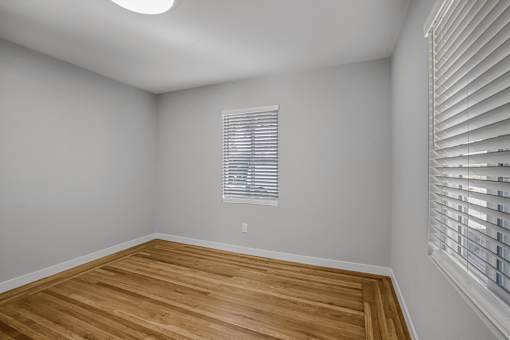 A room with wooden flooring and a window with blinds.