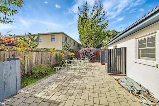 A backyard with a patio and a fence.