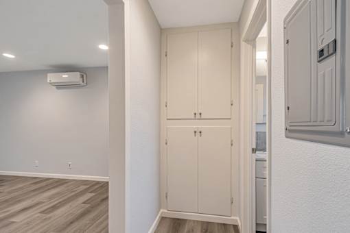 A white wall with a cabinet and a wall-mounted air conditioner.