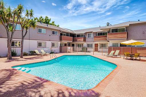A swimming pool surrounded by a fence and chairs.