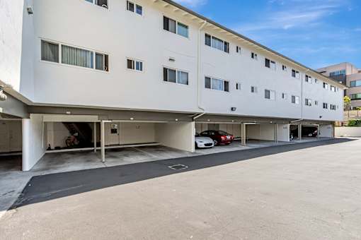 A white building with a parking garage in front.
