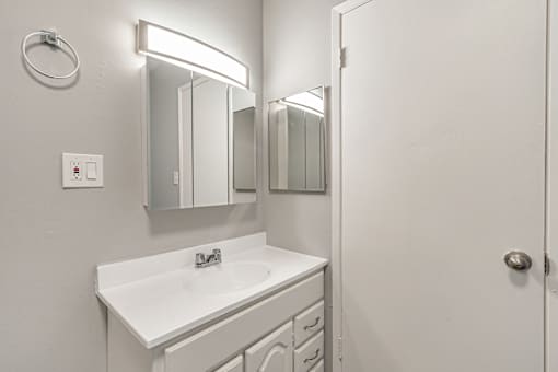 A white bathroom with a sink and mirror.