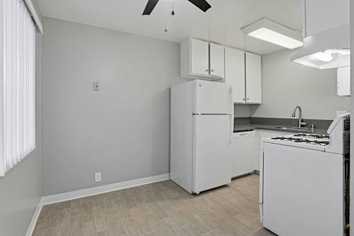 A kitchen with a white refrigerator and a fan on the ceiling.