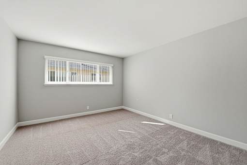A room with a window and carpeted floor.