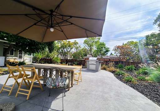 A patio with a table and chairs under an umbrella.