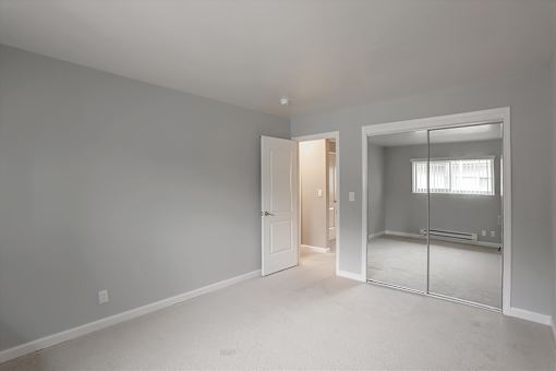 A room with a white door and a mirror on the wall.