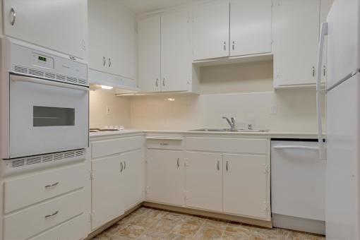 A kitchen with white cabinets and appliances.
