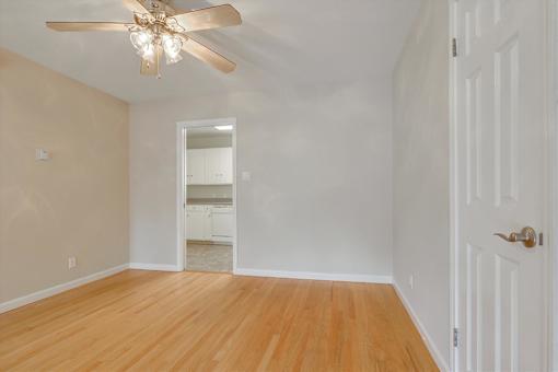A room with a ceiling fan and wooden floors.