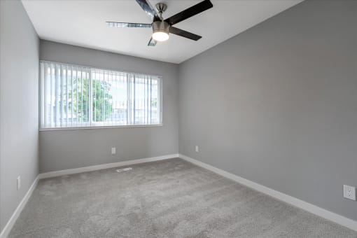 an empty living room with a ceiling fan and a window
