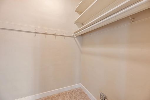 A white wall with a light switch and a white ceiling with a vent.