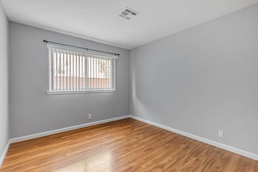 A room with wooden flooring and a window with blinds.