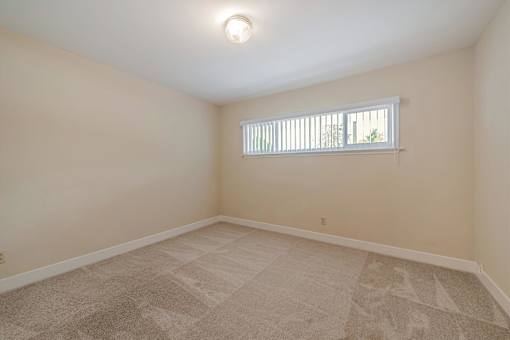 A room with a carpeted floor and a window with blinds.