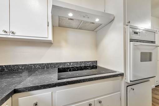 A kitchen with white cabinets and a marble countertop.