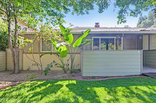 A house with a green lawn and a tree in front of it.