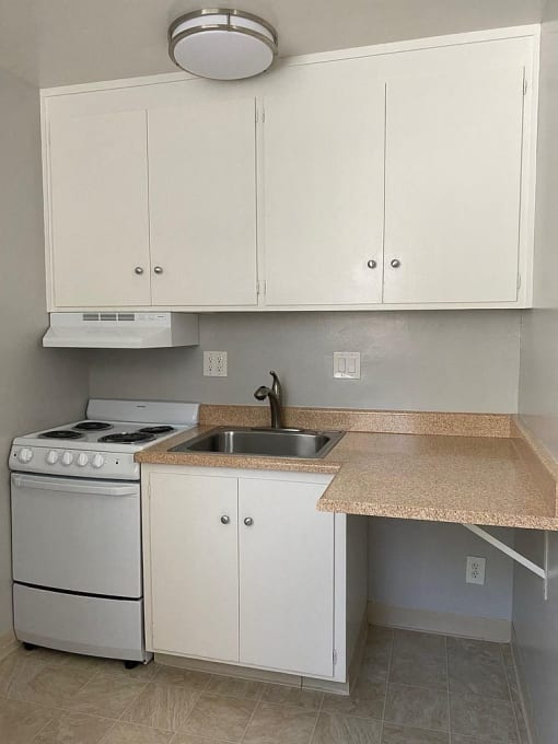 a kitchen with white cabinets and a stove and sink