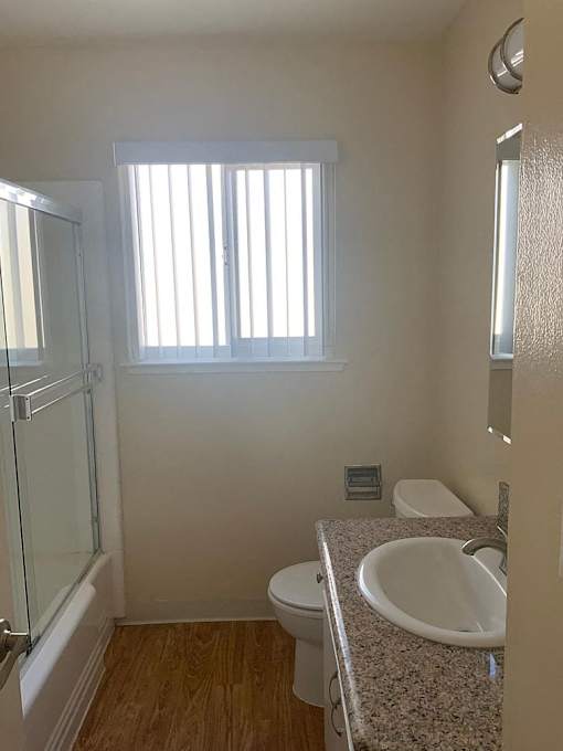 A bathroom with a sink, toilet, and a window.