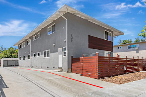 A modern house with a grey exterior and a red garage door.