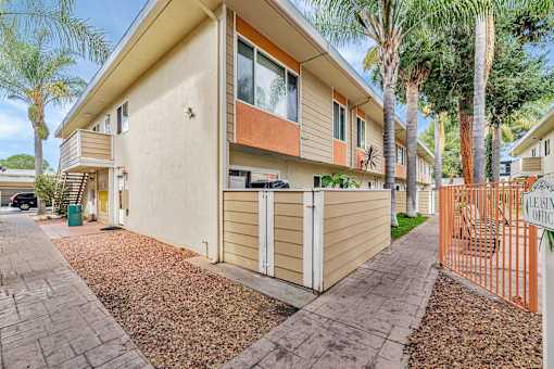 A beige house with a brown roof and a brown fence.