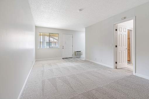 A sparsely furnished room with a door leading to another room.