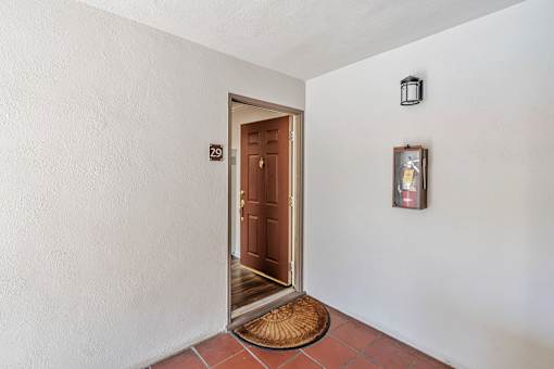 A brown door is at the end of a hallway with a number 29 on the wall above it.