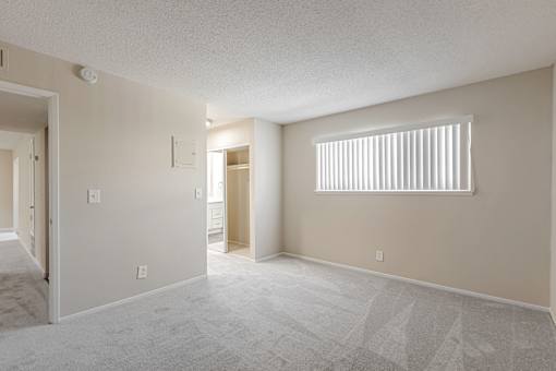 A room with a carpeted floor and a window with blinds.