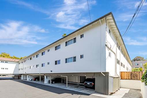 A white building with a car parked in front.