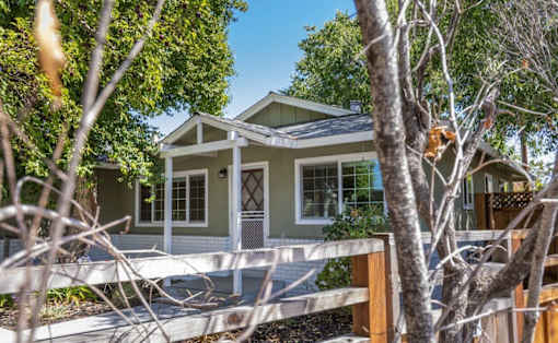 A house with a white fence and a tree in front.