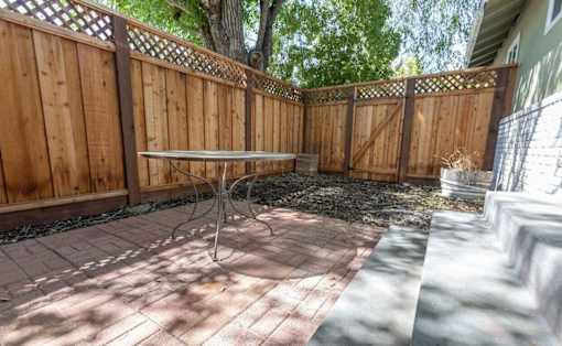 A backyard with a wooden fence and a table in the middle.