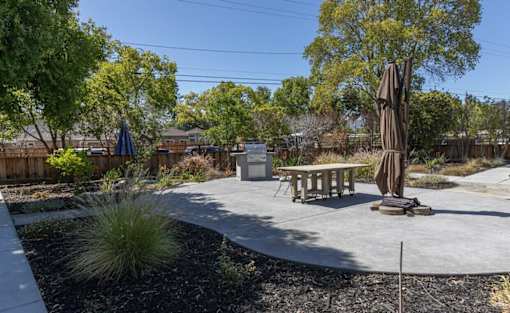 A park with a picnic table and a tree.