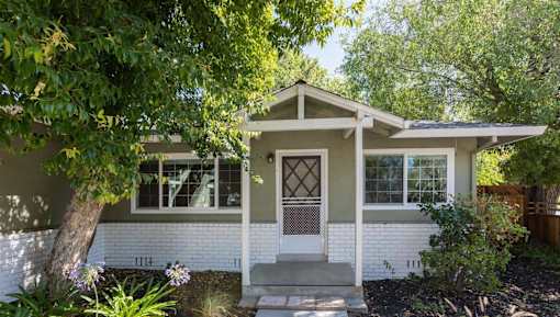 A white house with a brown door and a porch.