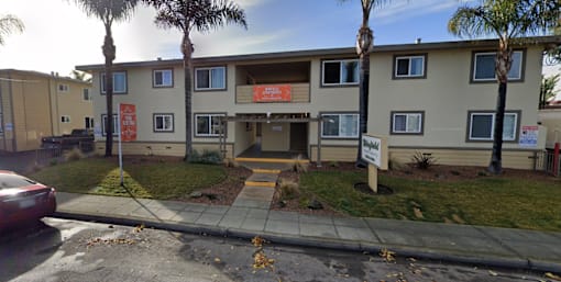 the front of an apartment building with palm trees