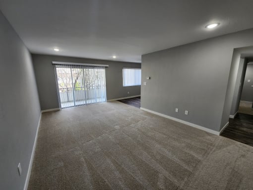a empty living room with a large window and gray walls