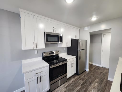 an empty kitchen with stainless steel appliances and white cabinets