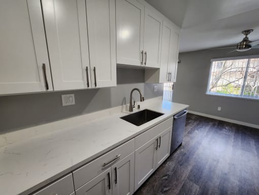 a kitchen with white cabinets and a sink and a window