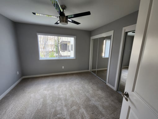 an empty room with a ceiling fan and a window