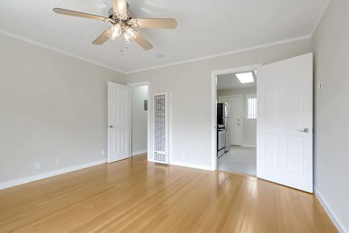 A room with a ceiling fan and wooden floors.