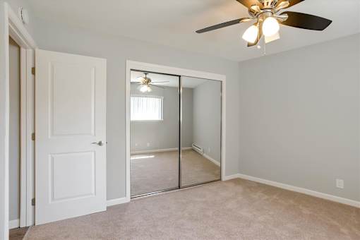 A room with a ceiling fan and a mirror on the wall.